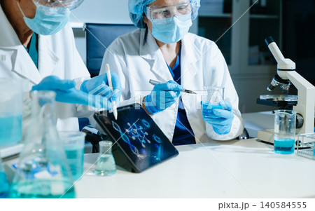 Scientists analyzing DNA genetics data on tablet in biotechnology laboratory with microscope and test tubes. Medical research, healthcare technology Scientists analyzing DNA genetics data on tablet in biotechnology laboratory with microscope and test tubes. Medical research, healthcare technology 140584555