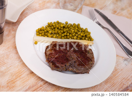 Dish of fried beef steak with green peas 140584584