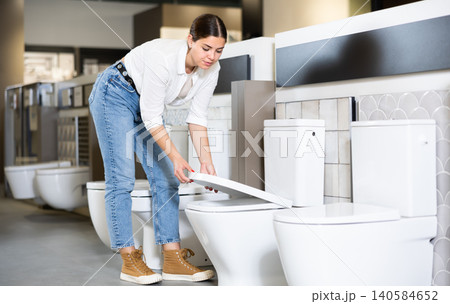 Female customer looking at white flush toilets on sale at modern store or shopping centre Female customer looking at white flush toilets on sale at modern store or shopping centre 140584652