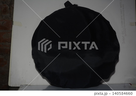 Black round decorative object with textured surface against light wall, textured Black round decorative object with textured surface against light wall, textured 140584660
