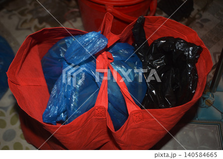 Red reusable fabric shopping tote bag containing plastic grocery bags Red reusable fabric shopping tote bag containing plastic grocery bags 140584665