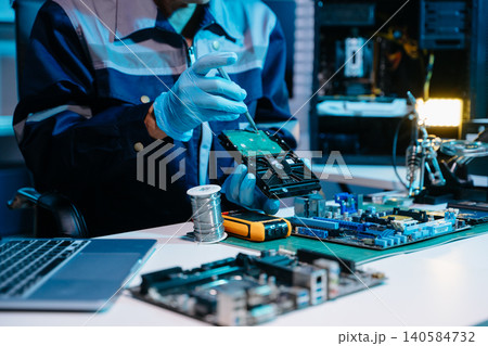 Closeup of expert soldering a green PCB board using precision tools. Ideal for electronics, circuit repair, engineering, tech 140584732