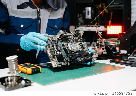 Professional senior technician holding and inspecting computer motherboard at high-tech electronics repair workstation Professional senior technician holding and inspecting computer motherboard at high-tech electronics repair workstation 140584758