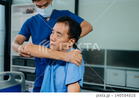 Physiotherapist assisting senior patient with shoulder rehabilitation in hospital clinic. Healthcare, recovery, pain relief and elderly mobility Physiotherapist assisting senior patient with shoulder rehabilitation in hospital clinic. Healthcare, recovery, pain relief and elderly mobility 140584818