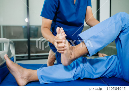 Physiotherapist stretching patient knee during physical therapy session in rehabilitation clinic. Healthcare treatment for injury recovery, mobility improvement Physiotherapist stretching patient knee during physical therapy session in rehabilitation clinic. Healthcare treatment for injury recovery, mobility improvement 140584945