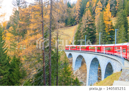 Red passenger train on Rhaetian railway in Canton Graubunden, Switzerland at autumn Red passenger train on Rhaetian railway in Canton Graubunden, Switzerland at autumn 140585251