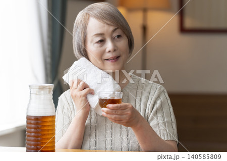 リビングで麦茶を注いで飲むシニア女性 リビングで麦茶を注いで飲むシニア女性 140585809