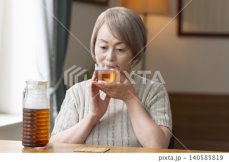 リビングで麦茶を注いで飲むシニア女性 140585819