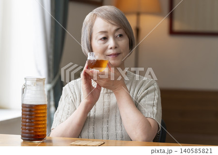 リビングで麦茶を注いで飲むシニア女性 140585821