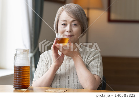 リビングで麦茶を注いで飲むシニア女性 リビングで麦茶を注いで飲むシニア女性 140585822
