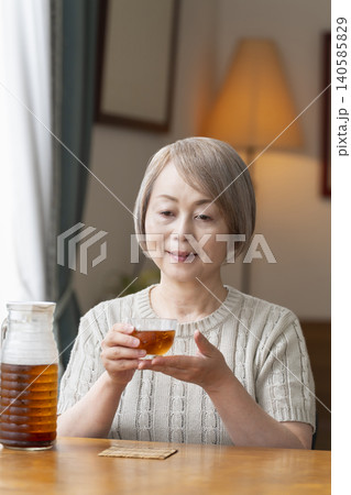 リビングで麦茶を注いで飲むシニア女性 リビングで麦茶を注いで飲むシニア女性 140585829