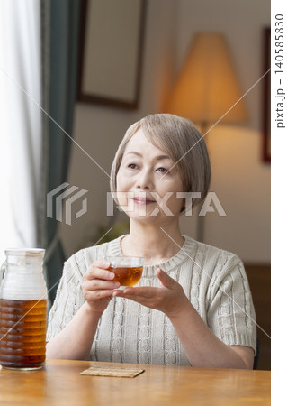 リビングで麦茶を注いで飲むシニア女性 リビングで麦茶を注いで飲むシニア女性 140585830