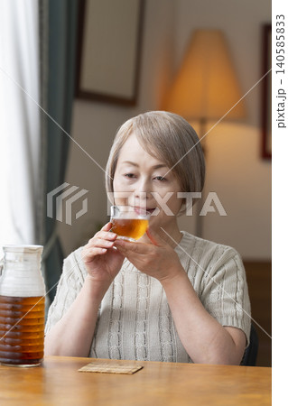 リビングで麦茶を注いで飲むシニア女性 リビングで麦茶を注いで飲むシニア女性 140585833