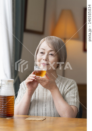 リビングで麦茶を注いで飲むシニア女性 140585834