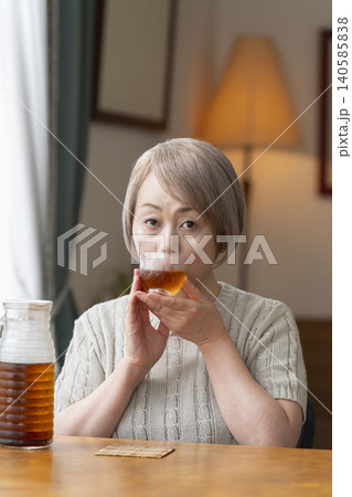 リビングで麦茶を注いで飲むシニア女性 リビングで麦茶を注いで飲むシニア女性 140585838