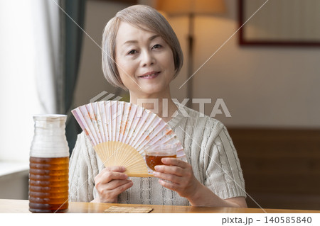 リビングで麦茶を注いで飲むシニア女性 リビングで麦茶を注いで飲むシニア女性 140585840