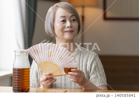 リビングで麦茶を注いで飲むシニア女性 リビングで麦茶を注いで飲むシニア女性 140585841