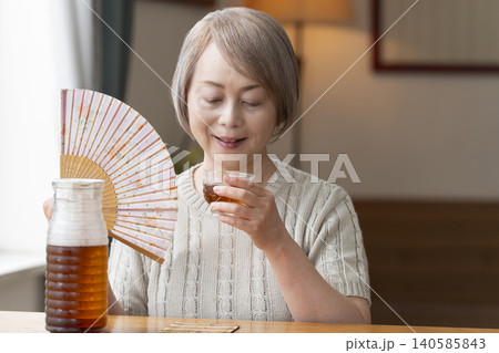 リビングで麦茶を注いで飲むシニア女性 140585843