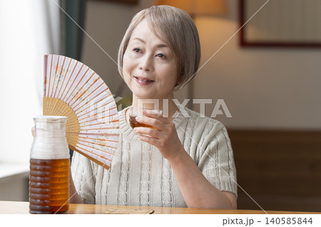 リビングで麦茶を注いで飲むシニア女性 リビングで麦茶を注いで飲むシニア女性 140585844