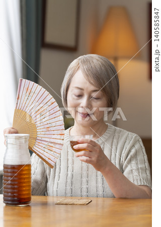 リビングで麦茶を注いで飲むシニア女性 リビングで麦茶を注いで飲むシニア女性 140585847