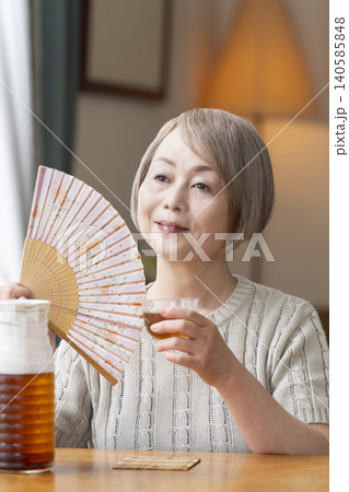 リビングで麦茶を注いで飲むシニア女性 リビングで麦茶を注いで飲むシニア女性 140585848