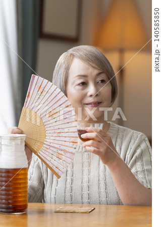 リビングで麦茶を注いで飲むシニア女性 リビングで麦茶を注いで飲むシニア女性 140585850