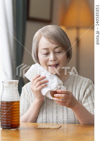 リビングで麦茶を注いで飲むシニア女性 140585851