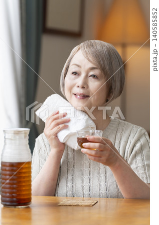 リビングで麦茶を注いで飲むシニア女性 リビングで麦茶を注いで飲むシニア女性 140585852