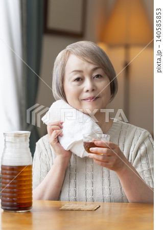 リビングで麦茶を注いで飲むシニア女性 リビングで麦茶を注いで飲むシニア女性 140585853
