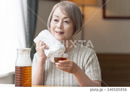 リビングで麦茶を注いで飲むシニア女性 リビングで麦茶を注いで飲むシニア女性 140585856