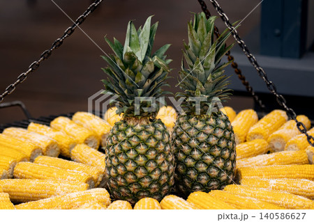 Two pineapples among yellow corn cobs street food stall Two pineapples among yellow corn cobs street food stall 140586627