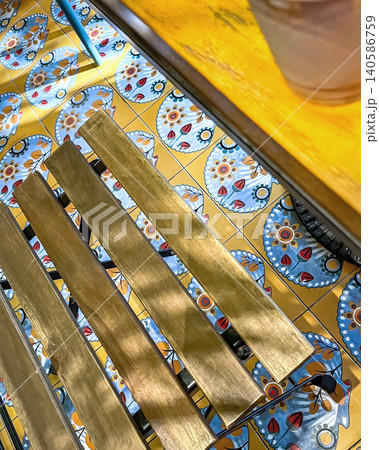 Sunlight streams onto a wooden bench over decorative tiles in a cafe 140586759