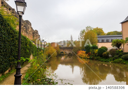 Small stone arched bridge across the Alzette River in the Grund, lower part of Luxembourg city, Luxembourg. Scenic autumn landscape 140588306