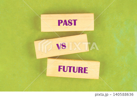 Two wooden blocks showing the words past and future are placed next to each other on a green surface. The blocks highlight a theme of time and change 140588636