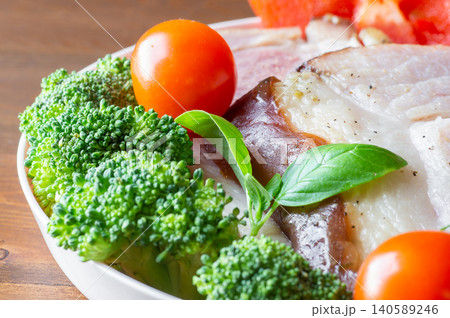 Close-up Baked HAM steaks lie on green lettuce leaves, cherry tomatoes and broccoli. 140589246