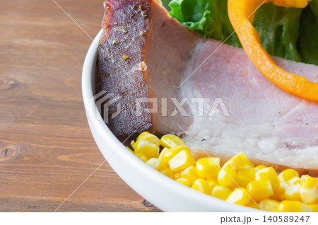 Baked HAM steaks lie on green lettuce leaves 140589247