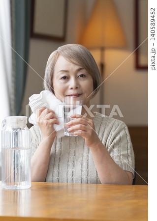 熱中症対策にリビングで水を飲むシニア女性 熱中症対策にリビングで水を飲むシニア女性 140589482