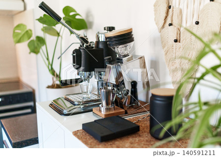 Home barista corner with a manual lever espresso machine and a single dose coffee grinder. Home barista corner with a manual lever espresso machine and a single dose coffee grinder. 140591211