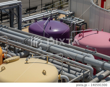 Large purple and pink chemical process tanks with interconnected pipes at a manufacturing plant. Large purple and pink chemical process tanks with interconnected pipes at a manufacturing plant. 140591300
