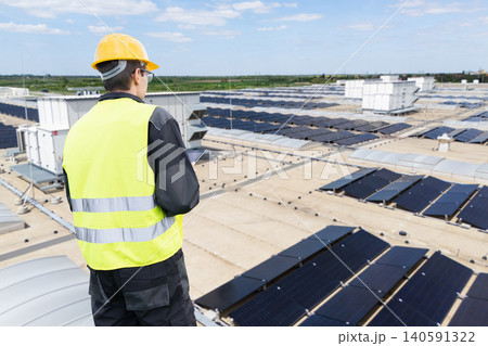 Technician managing large-scale solar power system on a commercial warehouse Technician managing large-scale solar power system on a commercial warehouse 140591322