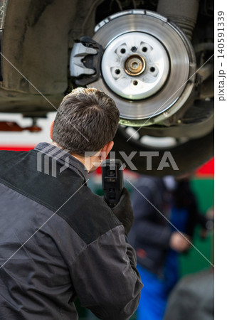 Serviceman checks the brake discs of a car. 140591339