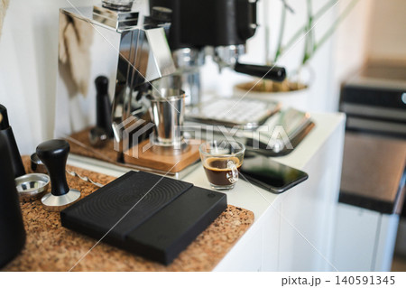 Home barista station with manual lever espresso machine, single dose grinder, and a smartphone on the counter. Home barista station with manual lever espresso machine, single dose grinder, and a smartphone on the counter. 140591345