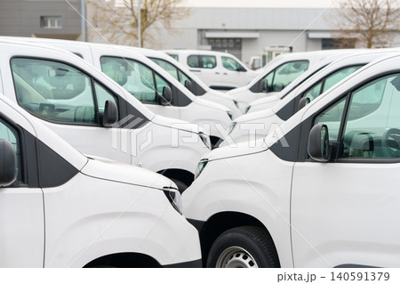 White delivery vans are parked in rows. Commercial fleet of vehicles 140591379