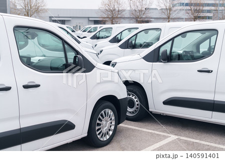 White delivery vans are parked in rows. Commercial fleet of vehicles White delivery vans are parked in rows. Commercial fleet of vehicles 140591401