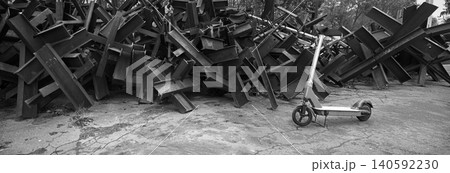 A scooter against the backdrop of iron anti-tank hedgehogs 140592230