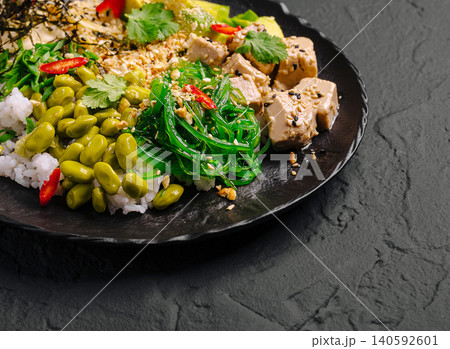 Tuna poke bowl with seaweed, edamame beans, and rice on black plate Tuna poke bowl with seaweed, edamame beans, and rice on black plate 140592601