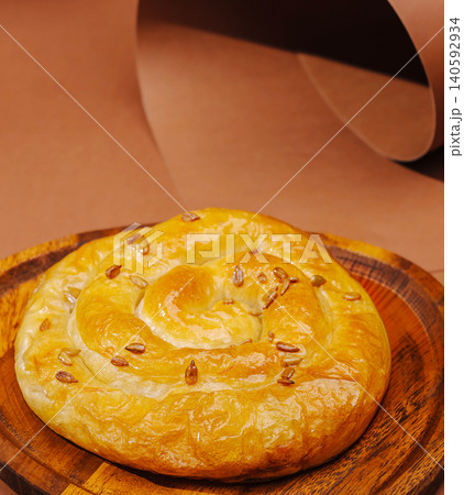 Baked spiral pastry with seeds on wooden tray Baked spiral pastry with seeds on wooden tray 140592934