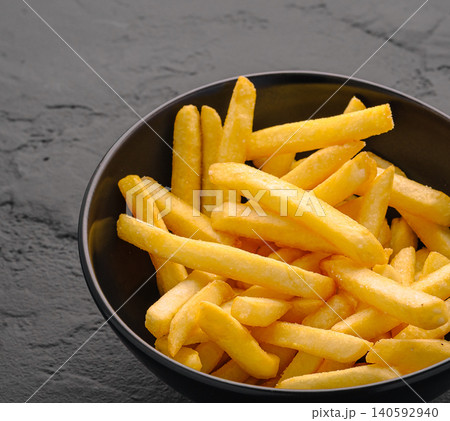 Golden salted french fries filling black bowl Golden salted french fries filling black bowl 140592940