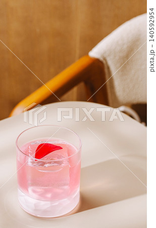 Pink cocktail with rose petal on light table Pink cocktail with rose petal on light table 140592954