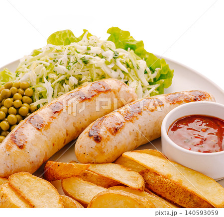 Grilled sausages served with salad, potatoes, and sauce on a plate 140593059